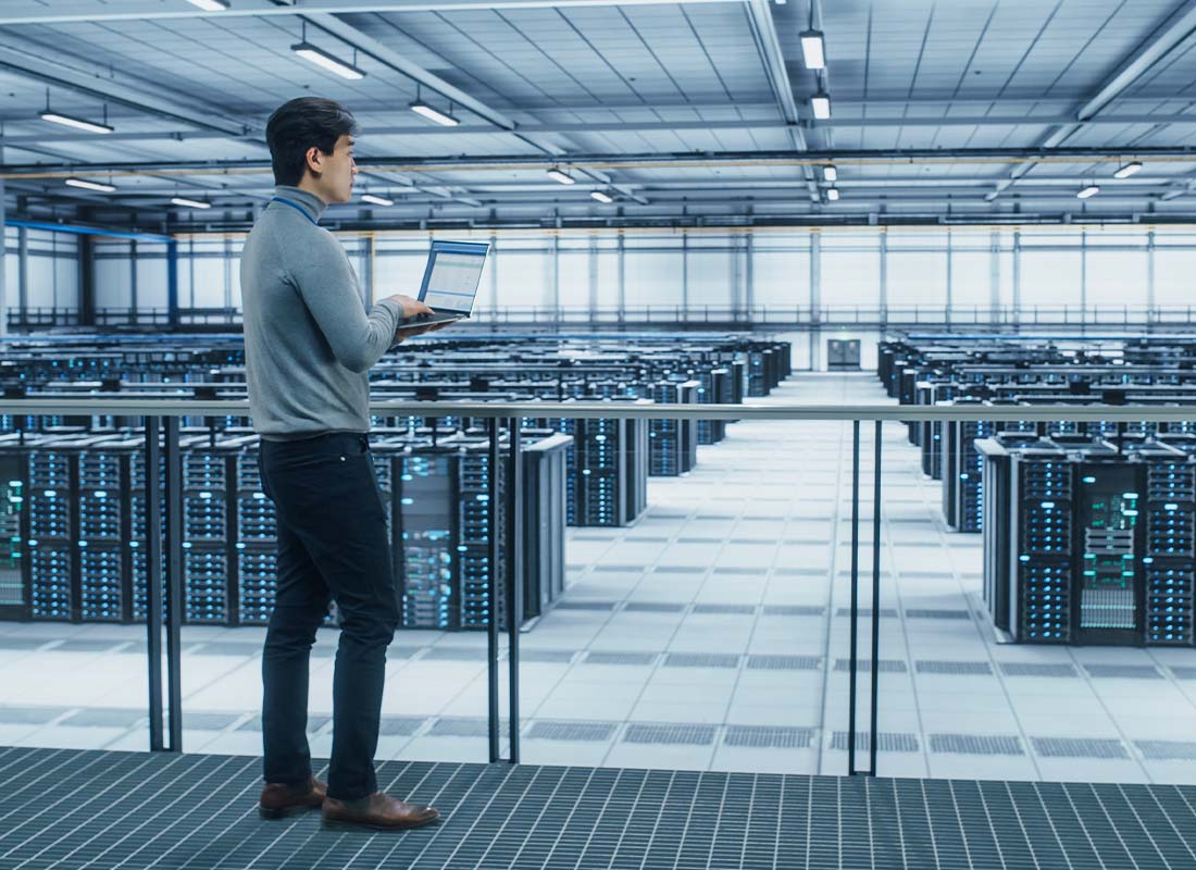 Cyber Security Contractor Insurance - Data Center Engineer Using His Laptop at a Server Farm Cloud Facility to Monitor Data Protection Network for Cyber Security